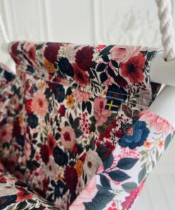Närbild på tyget till babygungan Höstäng: rosor, dahlior och höstblommor i rosa, rött och blått på ljus OEKO-TEX-bomull.
